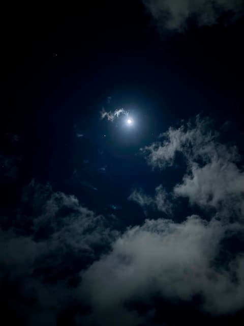 Full moon breaking through backlit night clouds